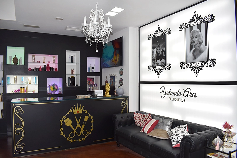 Interior de peluquería donde se ve mostrador y sillón de la zona de espera.